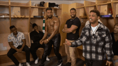 A Group Of Men Are Standing In A Locker Room And One Of Them Is Wearing A Shirtless Shirt GIF