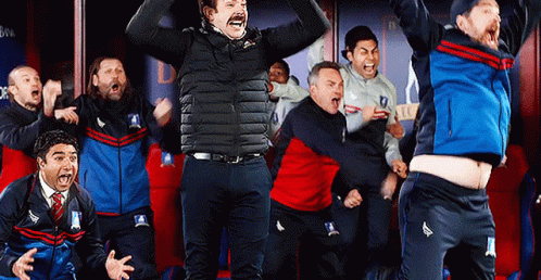 A Group Of Men Are Standing In A Locker Room Celebrating A Win . GIF