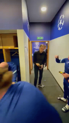 A Group Of Men Are Standing In A Locker Room With A Sign On The Wall That Says Champions League GIF