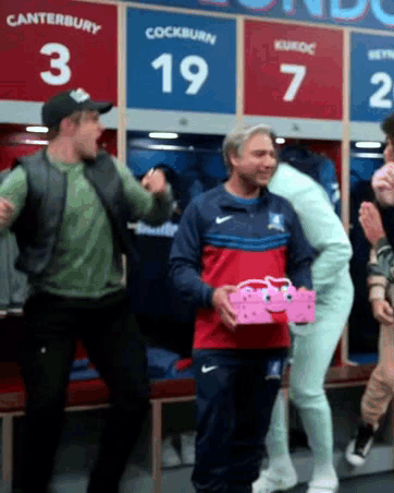 A Group Of Men Are Standing In A Locker Room With The Number 19 On The Wall GIF