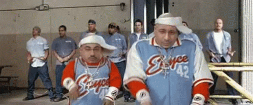 A Group Of Men Are Standing In A Room And One Of Them Is Wearing A Jacket That Says Stance 42 GIF