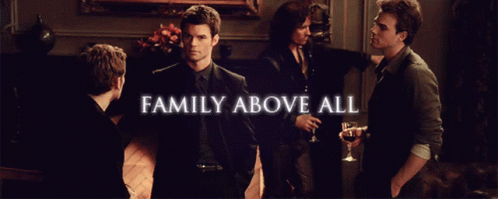 A Group Of Men Are Standing In A Room With The Words Family Above All GIF