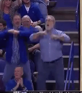 a group of men are standing in a stadium with their arms outstretched during a basketball game .
