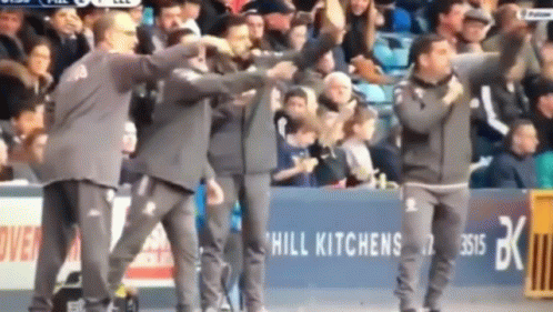 A Group Of Men Are Standing In Front Of A Hill Kitchens Sign GIF