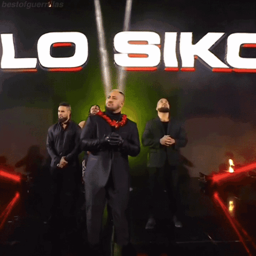 A Group Of Men Are Standing In Front Of A Large Sign That Says Lo Siko GIF