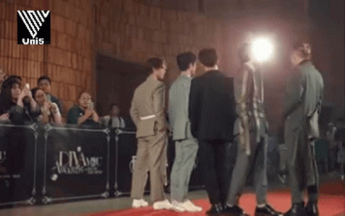 A Group Of Men Are Standing In Front Of A Podium That Says Uni5 GIF