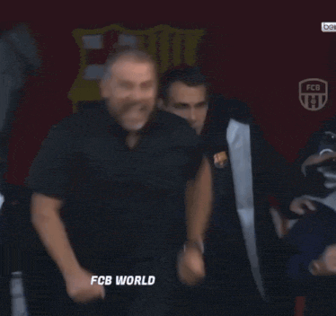 A Group Of Men Are Standing In Front Of A Sign That Says " Fcb World " GIF
