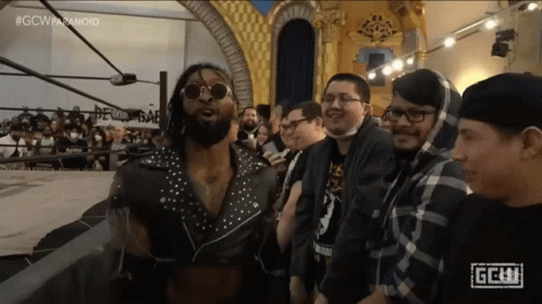 A Group Of Men Are Standing In Front Of A Sign That Says Gcw On It GIF
