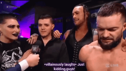A Group Of Men Are Standing Next To Each Other And Laughing While A Man Talks Into A Microphone . GIF