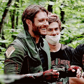 A Group Of Men Are Standing Next To Each Other In A Forest . GIF
