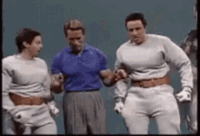 A Group Of Men Are Standing Next To Each Other In A Room . GIF