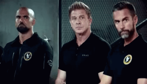 A Group Of Men Are Standing Next To Each Other In A Room . GIF