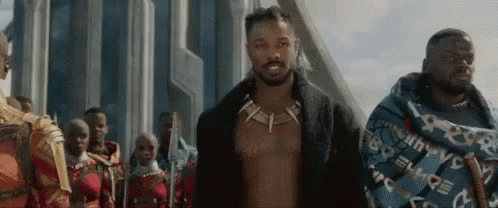 A Group Of Men Are Standing Next To Each Other In Front Of A Building In A Movie . GIF