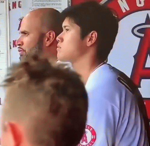 A Group Of Men Are Standing Next To Each Other In Front Of A Sign That Says Angels On It . GIF