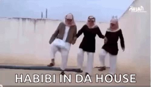 A Group Of Men Are Standing Next To Each Other In The Desert Holding Hands And Dancing . GIF