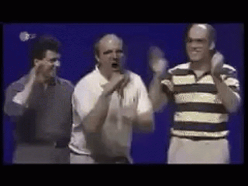 A Group Of Men Are Standing Next To Each Other On A Stage And Applauding . GIF