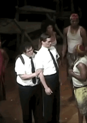 A Group Of Men Are Standing Next To Each Other On A Stage In A Dark Room . GIF