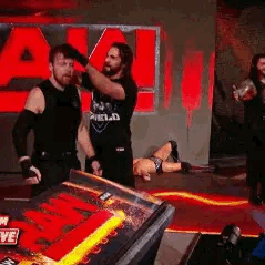 A Group Of Men Are Standing Next To Each Other On A Stage In Front Of A Red Sign . GIF