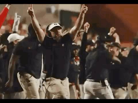 a group of men are standing on a football field with their hands in the air .
