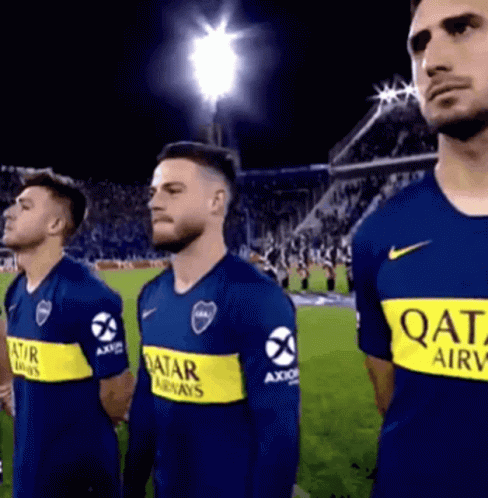 a group of men are standing on a soccer field wearing qatar airways shirts .
