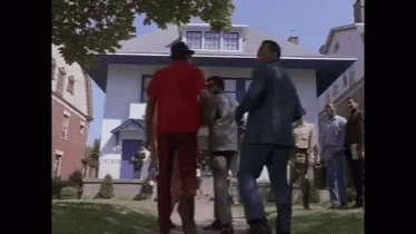 A Group Of Men Are Standing Outside Of A House Talking To Each Other . GIF