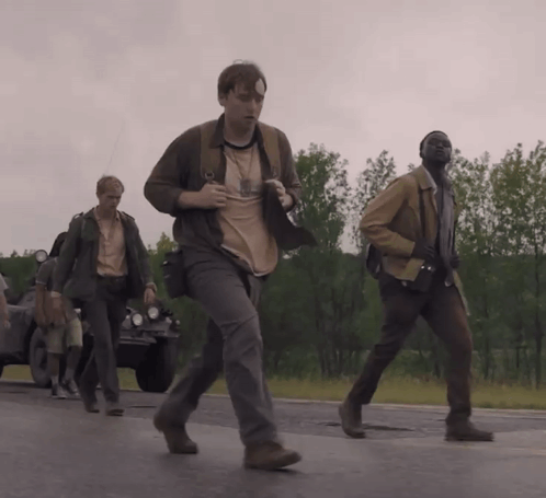 A Group Of Men Are Walking Down A Road And One Of Them Is Wearing A Shirt That Says ' A ' GIF