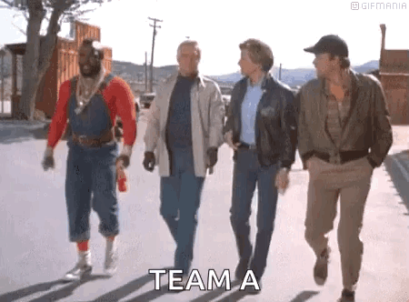 A Group Of Men Are Walking Down A Street With The Words `` Team A '' Written On The Sidewalk . GIF