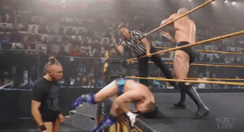 A Group Of Men Are Wrestling In A Ring While A Referee Looks On . GIF