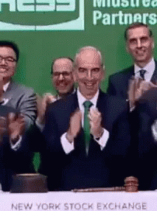 A Group Of Men Clapping In Front Of A New York Stock Exchange Table GIF