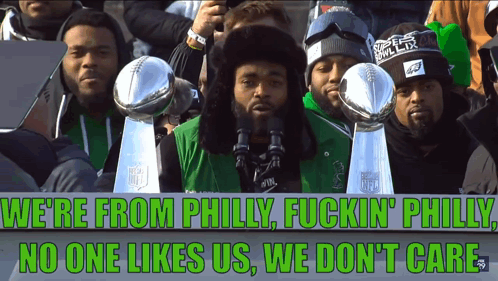 A Group Of Men Holding Trophies And A Sign That Says We 'Re From Philly Fuckin Philly No One Likes Us GIF