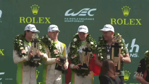 A Group Of Men Holding Trophies In Front Of A Rolex Logo GIF