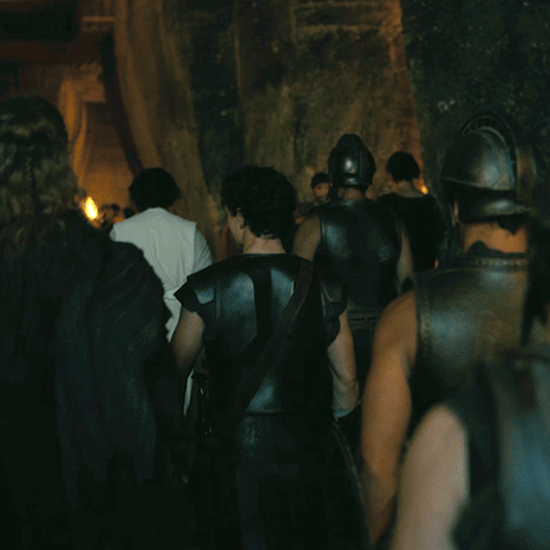 A Group Of Men In Armor Are Walking Through A Dark Room GIF