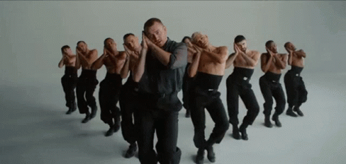 A Group Of Men In Black Pants Are Dancing In A Row . GIF