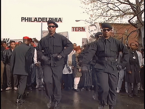 A Group Of Men In Black Uniforms Are Marching In Front Of A Sign That Says Philadelphia GIF