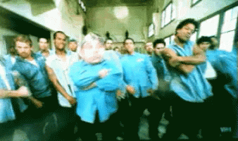 A Group Of Men In Blue Shirts Are Standing In A Hallway GIF