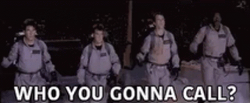 A Group Of Men In Ghostbusters Costumes Are Walking In The Dark And Talking To Each Other . GIF