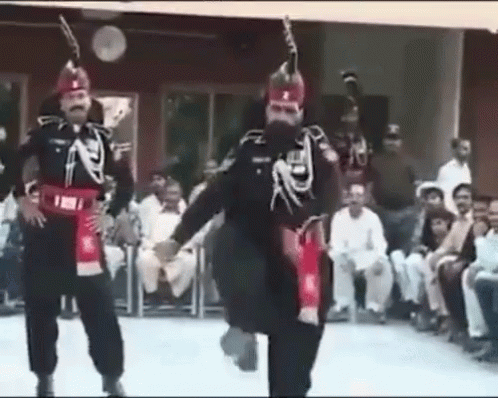 A Group Of Men In Military Uniforms Are Dancing In Front Of A Crowd Of People . GIF