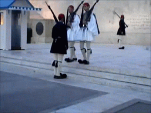 A Group Of Men In Military Uniforms Are Standing On A Sidewalk Holding Guns GIF