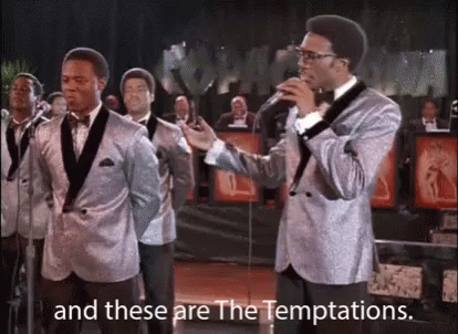 A Group Of Men In Suits And Bow Ties Are Singing Into Microphones On A Stage . GIF
