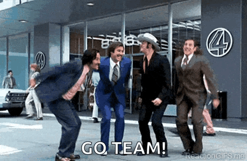 A Group Of Men In Suits And Ties Are Dancing In Front Of A Building With The Words Go Team Written On The Bottom . GIF