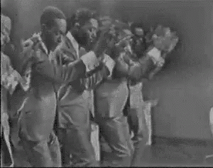 A Group Of Men In Suits And Ties Are Dancing On A Stage . GIF