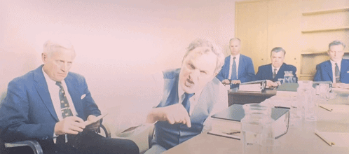 A Group Of Men In Suits And Ties Are Sitting Around A Table With Water Bottles GIF
