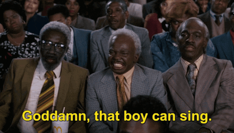 A Group Of Men In Suits And Ties Are Sitting In A Crowd And One Of Them Is Saying Goddamn That Boy Can Sing GIF
