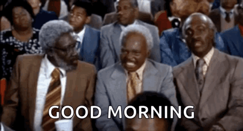A Group Of Men In Suits And Ties Are Sitting In A Room With The Words `` Good Morning '' Written On The Screen . GIF
