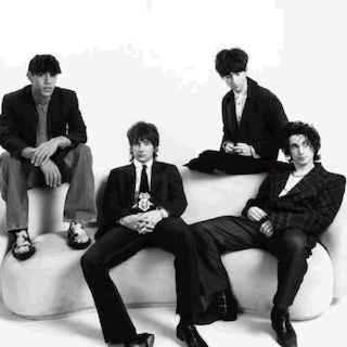 A Group Of Men In Suits And Ties Are Sitting On A White Couch . GIF