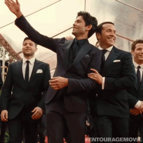 A Group Of Men In Suits And Ties Are Standing In Front Of A Tent With The Entourage Movie Written On The Bottom GIF