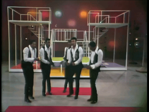 A Group Of Men In Suits And Vests Are Dancing On A Stage GIF