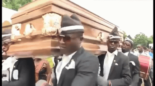 A Group Of Men In Suits Are Carrying A Coffin . GIF