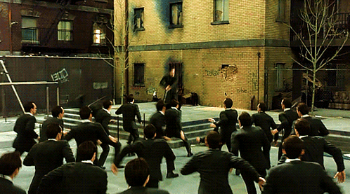 A Group Of Men In Suits Are Dancing In Front Of A Brick Building That Has Graffiti On It That Says ' Ec ' GIF