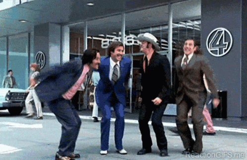 A Group Of Men In Suits Are Dancing In Front Of A Building With The Number 4 On It . GIF